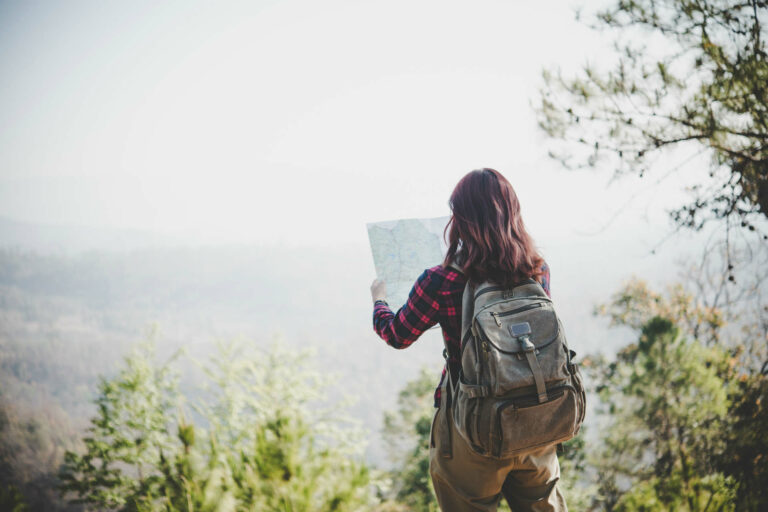 Woman hiking on a mountain range looking at a map